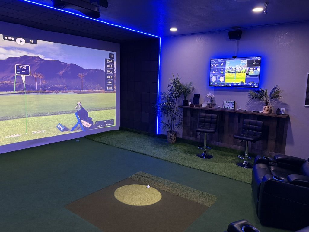 Custom home golf simulator room with lounge seating, television, and bar area
