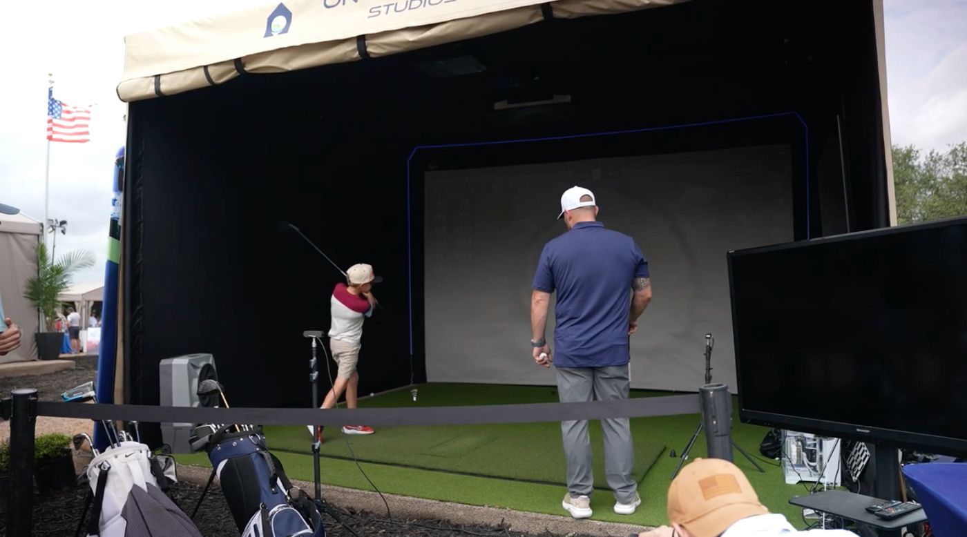 Young golfer taking a swing inside the mobile golf simulator