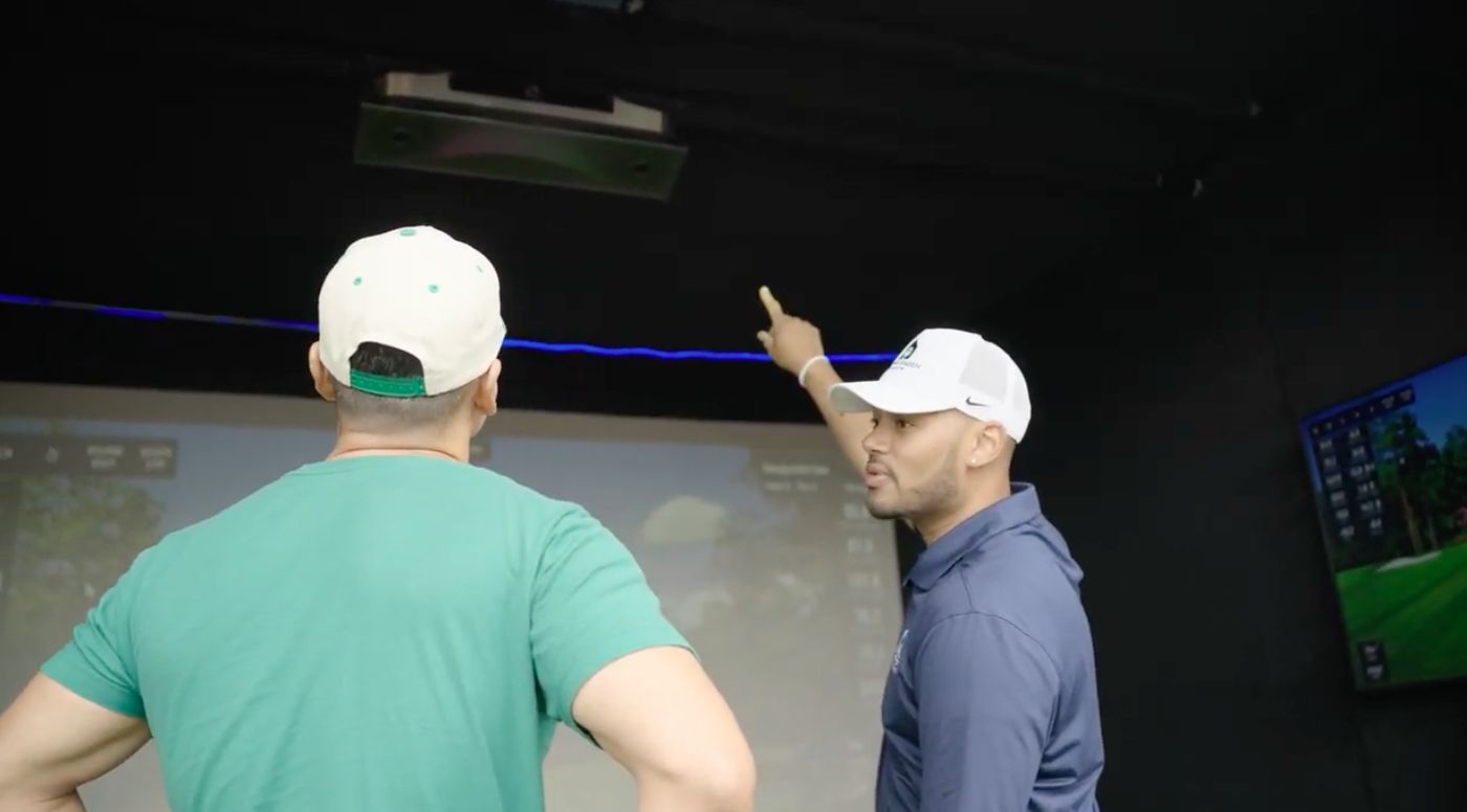 Event attendant explaining the mobile golf simulator equipment to a guest