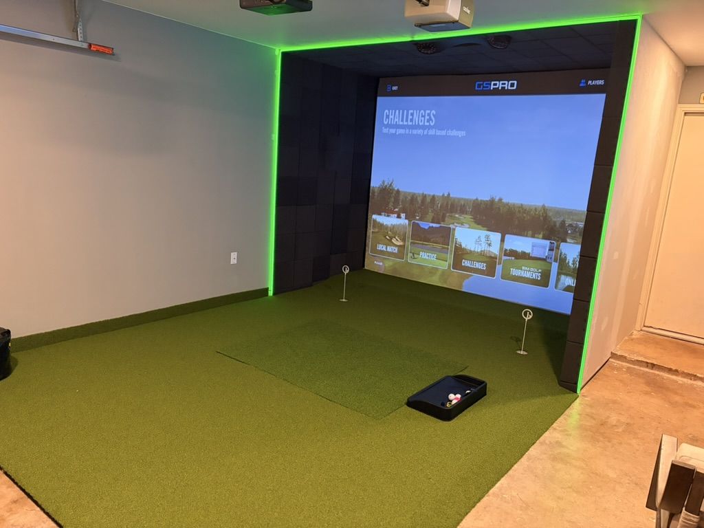 Garage golf simulator with green LED lighting and full turf flooring