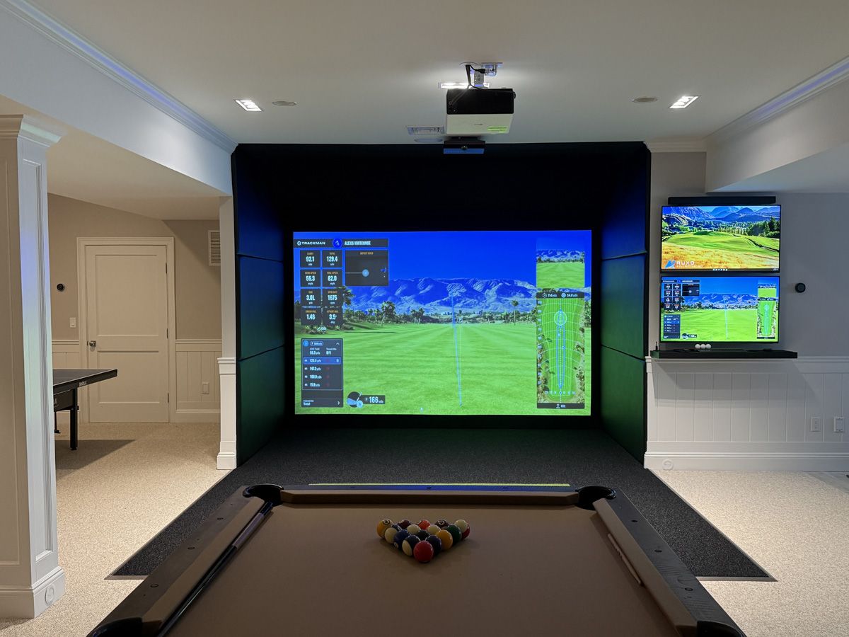 Basement golf simulator entertainment room with pool table and dual displays