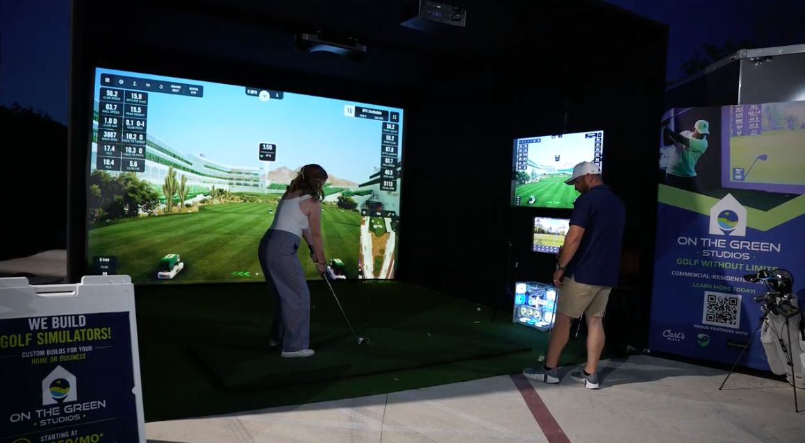Guest playing in a mobile golf simulator while an event attendant assists