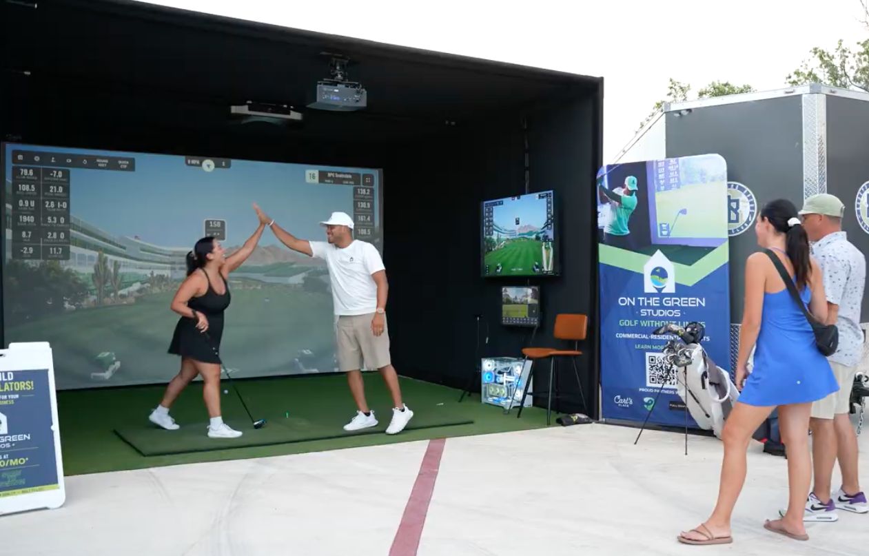 Guests celebrating with a high five after a mobile golf simulator shot