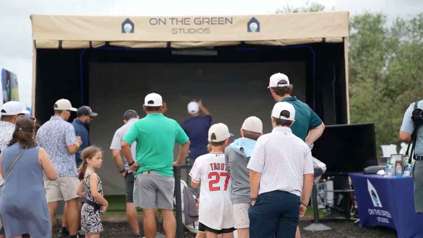Families and golf fans watching the mobile simulator at a large outdoor event
